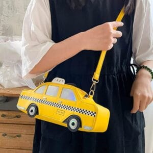 Femme en robe Svarte avec des manches Vithes portant un sac Gul en bandoulière en forme de taxi