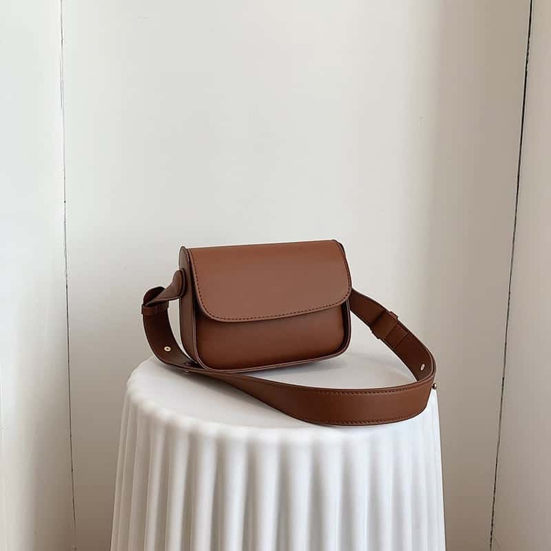 Photo d'un sac pochette bandoulière en cuir synthétique Brun de syle minimaliste posé sur un présentoir Vit texturé