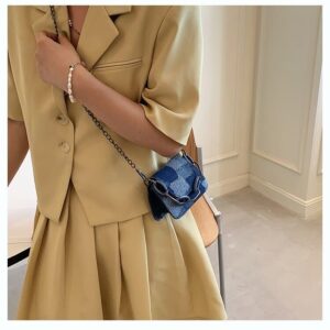 Femme en ensemble beige portant un mini sac Blå en jean avec une chaîne en bandoulière