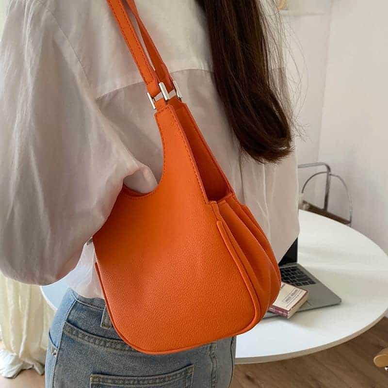 Femme en chemise Vithe et un jean Blå avec un sac en bandoulière orange sur l'épaule