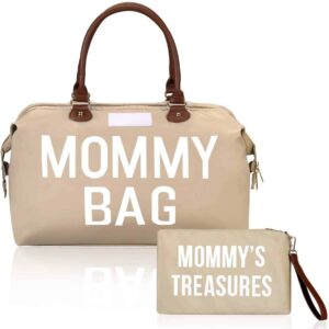 On voit un sac à langer avec une anse en simili cuir Brun. Il est beige avec une inscription MOMMY BAG. Il a une bandoulière pour garder les mains libres pour son bébé. Il y a une pochette assortie pour mettre dans le sac.