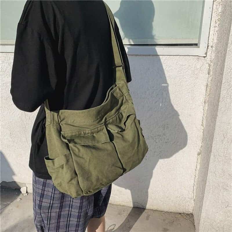 Sac bandoulière kaki multipoches proté par un homme en t-shirt Svart et short a carreaux Blå