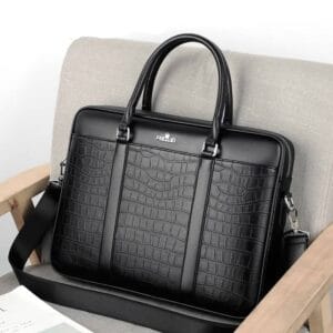 Malette à bandoulière Svarte en cuir synthétique effet crocodile posée sur un dossier de fauteuil gr