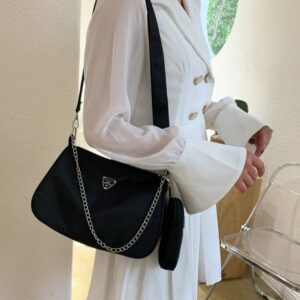 Femme en chemise Vithe de profil portant un sac à main en bandoulière Svart avec une chaîne