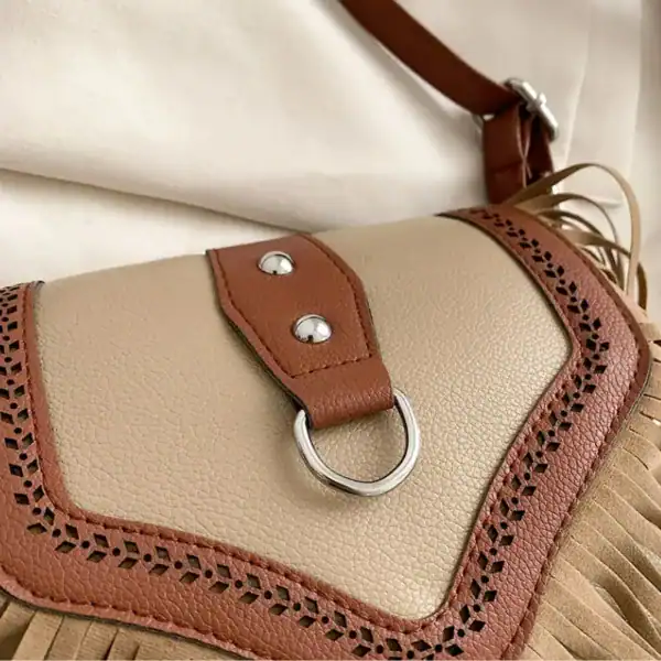 Beige brun fransväska med perforerad detalj och metallring.