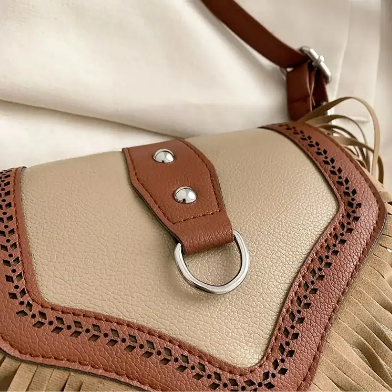 Beige brun fransväska med perforerad detalj och metallring.