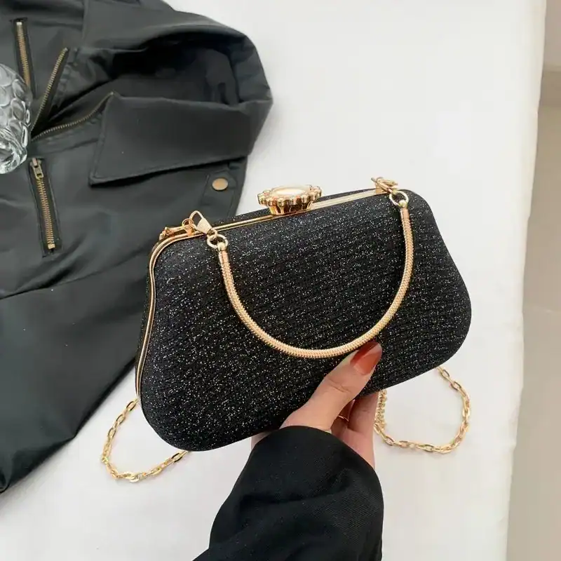 Svart glittrig clutch med guld kedja och handtag, perfekt för kvällsklänningar.