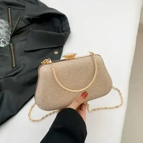 Beige clutch med gyllene kedjehandtag och smyckad snäppa.