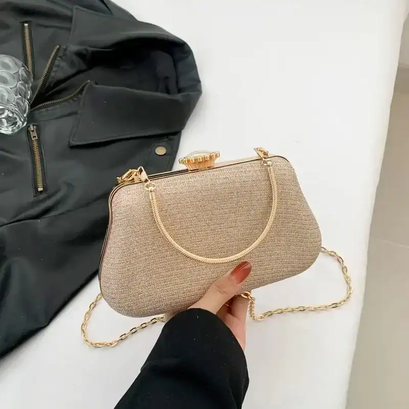 Beige clutch med gyllene kedjehandtag och smyckad snäppa.