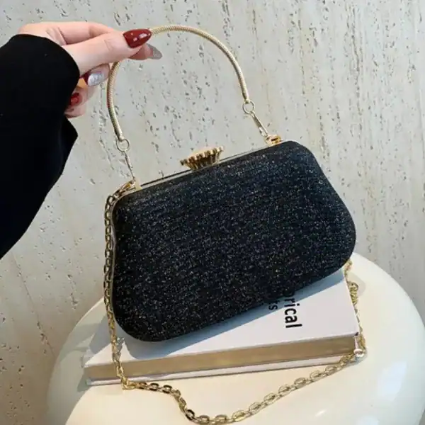 Svart glittrande clutch med guldhandtag och kedja, perfekt för kvällskläderna.