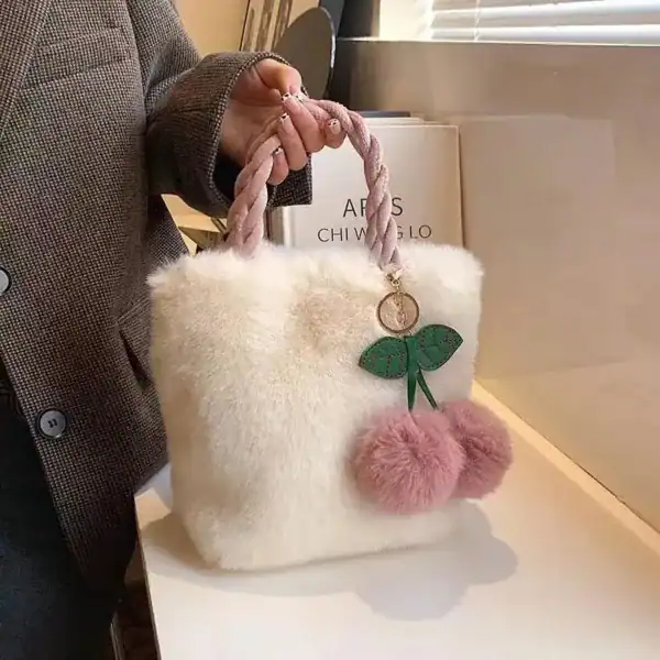 Beige fluffig väska med rosa pomponer och grön blomma.