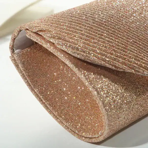 Beige glittrig clutch med strukturerad yta och eleganta design.