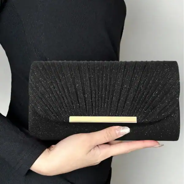 Svart glittrig clutch med guldlock och plisserad design.