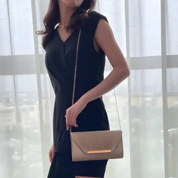 Beige glittrig clutch med gyllene kedjehandtag, perfekt för kvällsklänning.