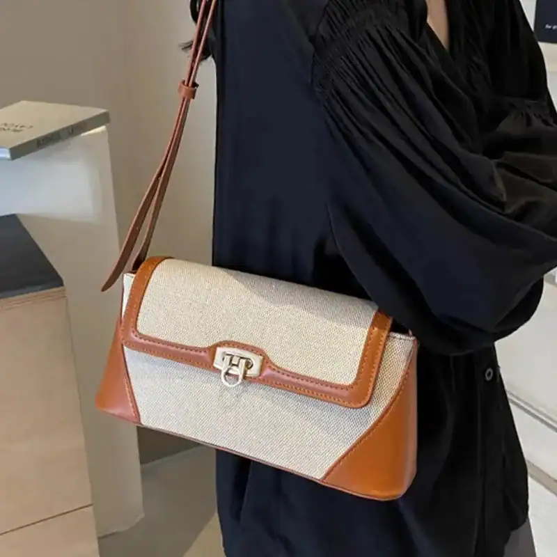 Beige handväska med brunt läder och silverfärgad snäcka.