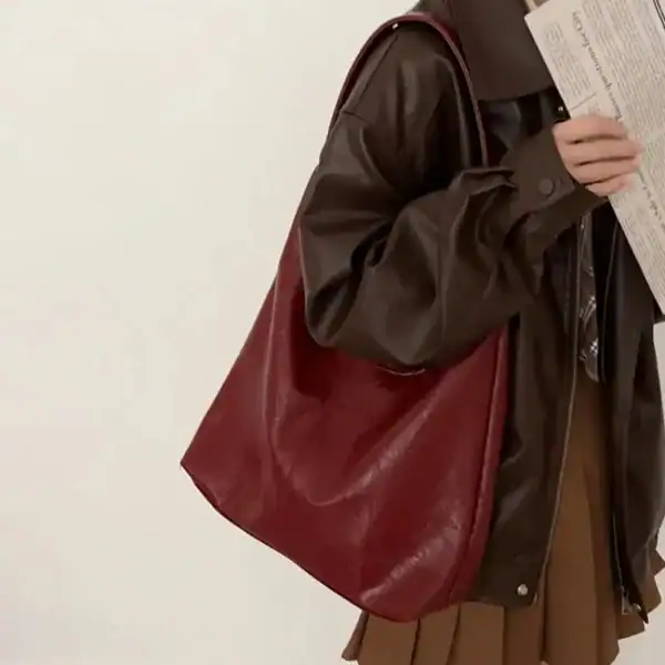 Beige hoboväska i röd läderliknande material, bärt av person i mörk jacka.