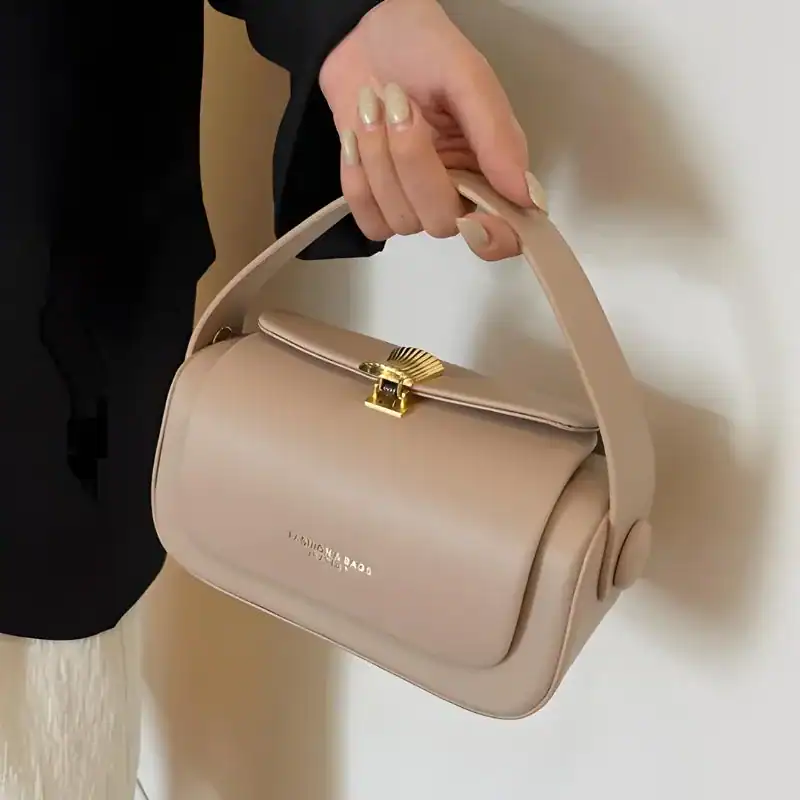 Beige liten crossbody axelväska med guldaktig snäppa och handtag.