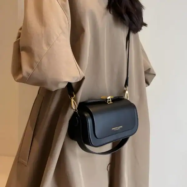 Svart liten crossbody axelväska med guldaccent, bära över axeln eller som handväska.