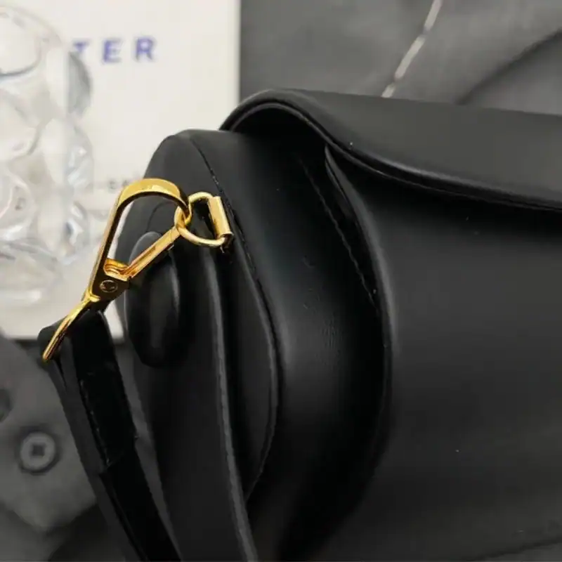 Svart liten crossbody axelväska med guld fäste och elegant design.