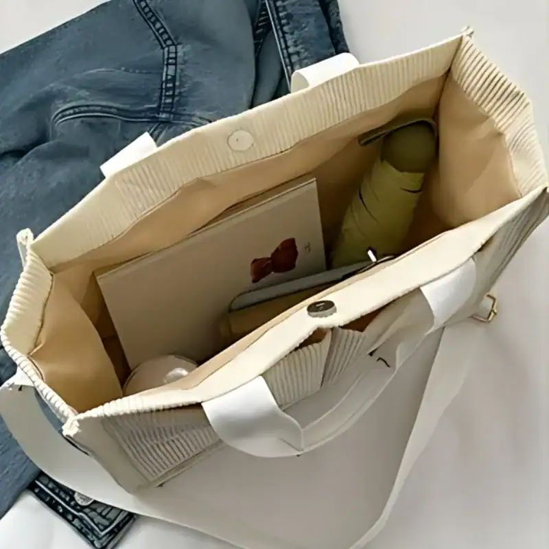 Beige manchesterväska med innehåll, böcker och paraply, stilig axelväska för vardag.
