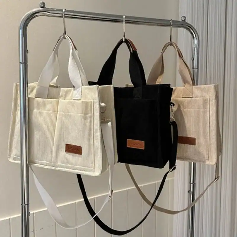 Beige och svarta manchesterväska i corduroy, hängande på stålträdsställning.
