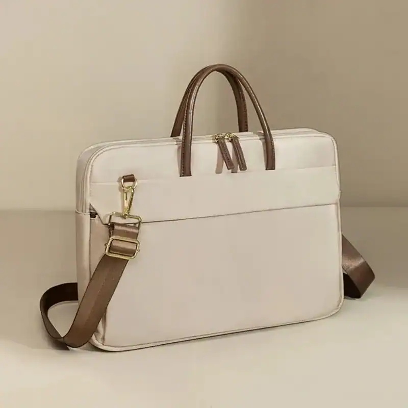 Beige nylon datorväska med bruna handtag och axelrem.