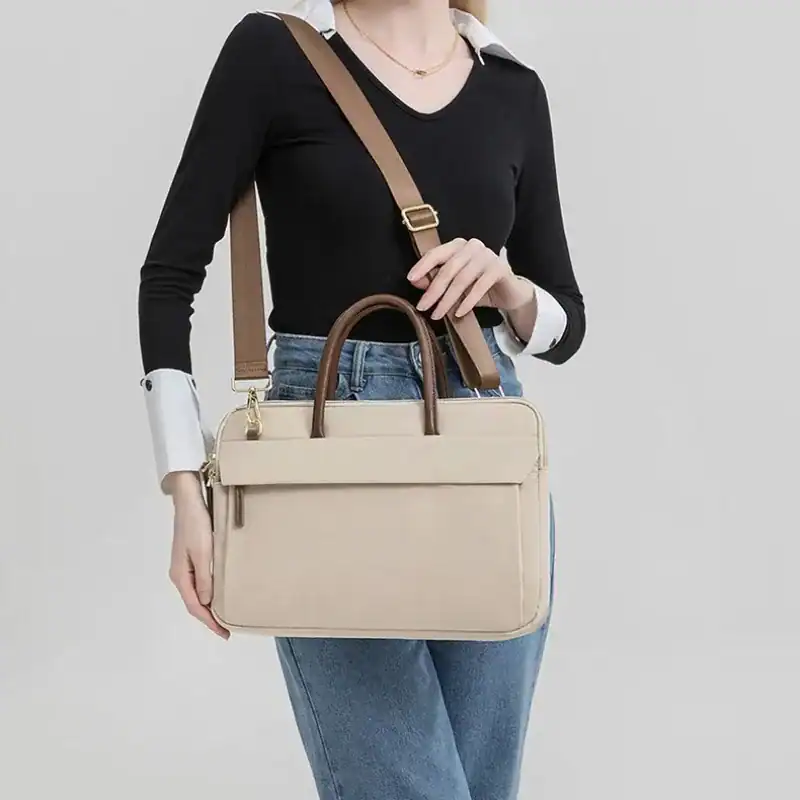 Beige nylon datorväska med axelrem och handtag för kvinnor.