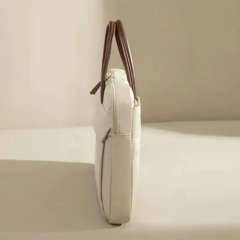 Beige nylon datorväska med bruna handtag och zippad framsida.