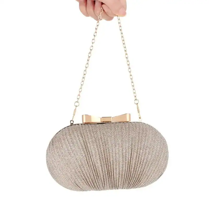 Beige oval clutch med glittrig textur och guldaktig hängsmycke.