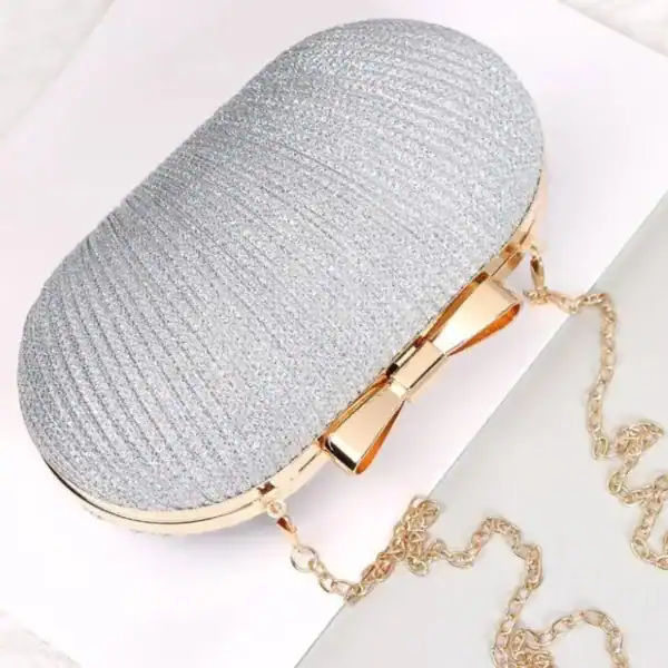 Beige oval clutch med gyllene snodd och knapp, perfekt för kvällskläderna.