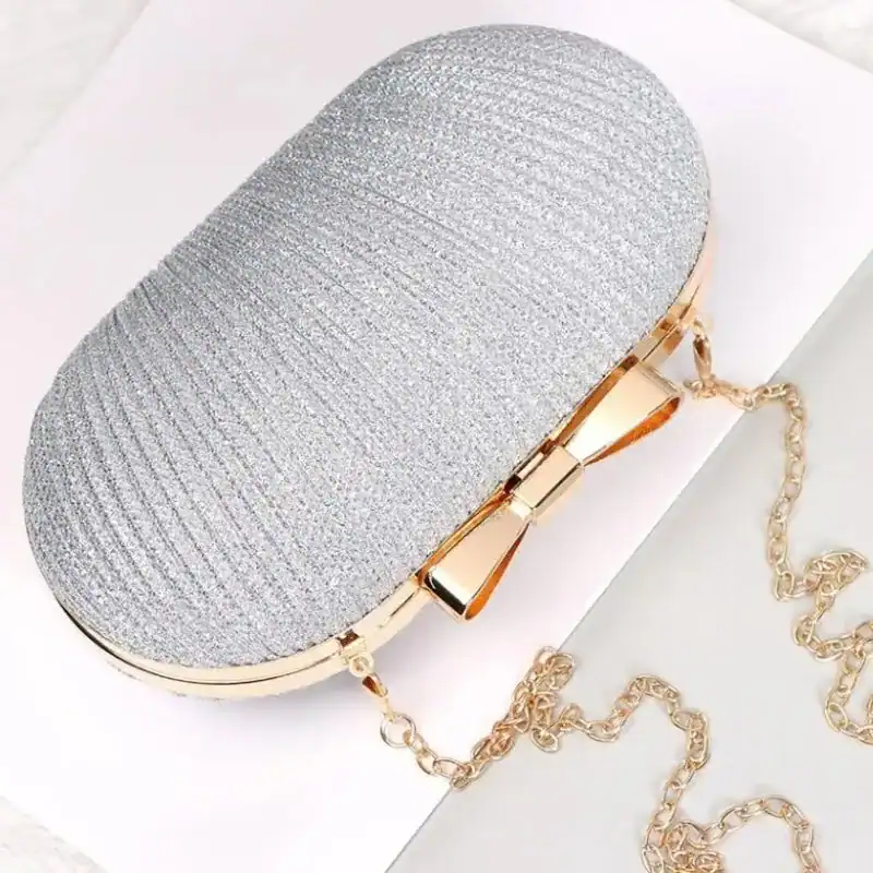 Beige oval clutch med gyllene snodd och knapp, perfekt för kvällskläderna.