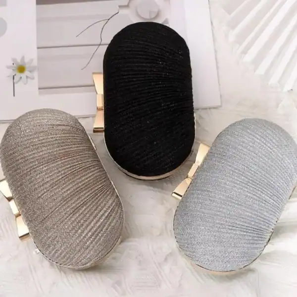 Oval clutch i beige, svart och silver med guld detaljer.