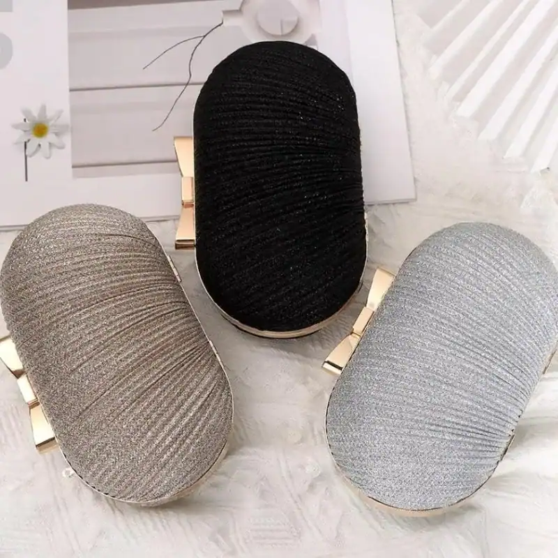 Oval clutch i beige, svart och silver med guld detaljer.