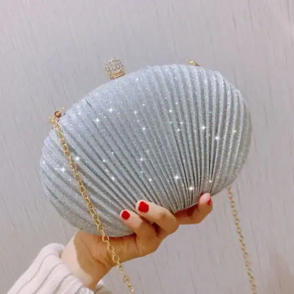 Beige oval festclutch med glittrande yta och gyllene kedja.