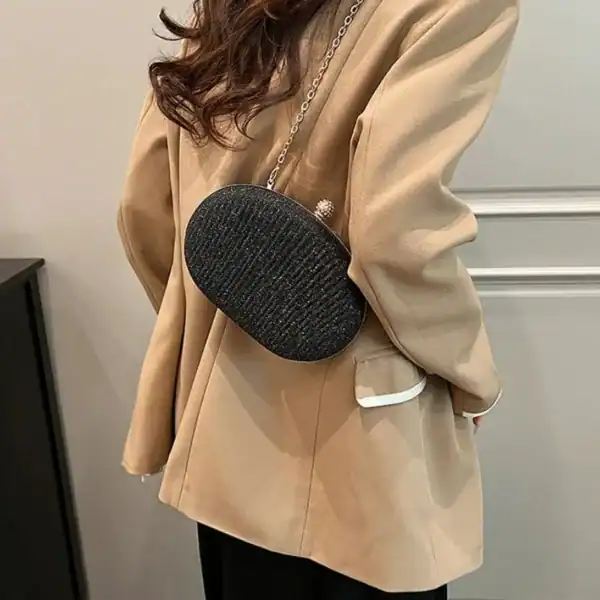 Beige oval festclutch med silver kedja och texturerad yta.