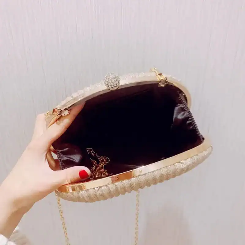 Beige oval festclutch med gyllene krok och pärlbesättning.