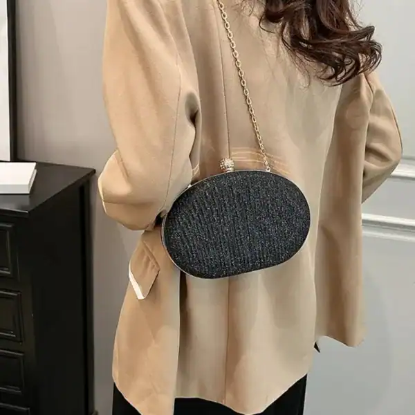 Beige oval festclutch med glittrig textur och gyllene kedja.