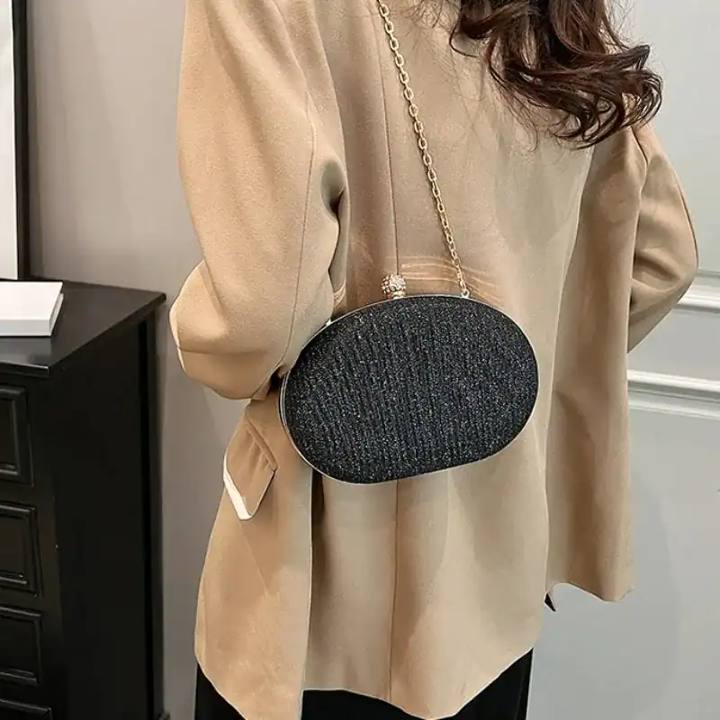 Beige oval festclutch med glittrig textur och gyllene kedja.