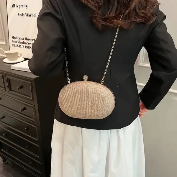 Beige oval festclutch med glittrande textur och kedjehängare.