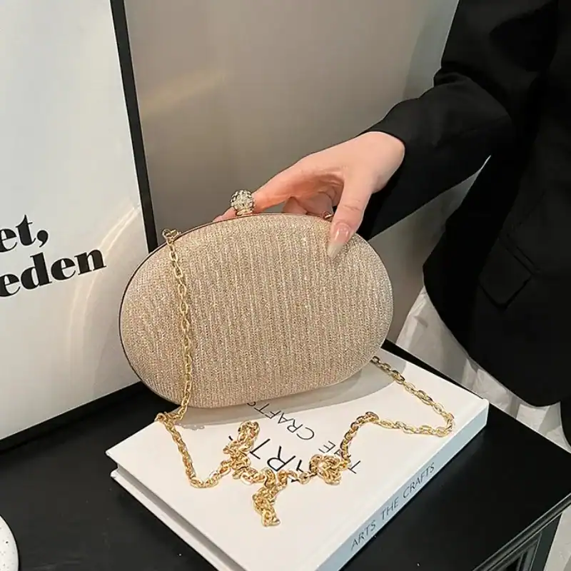 Beige oval festclutch med gyllene kedjehandtag och glittrande yta.