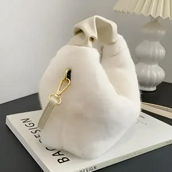 Beige pälsväska med handtag och guldtonad snabbfästning.