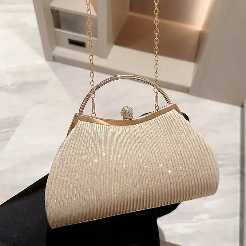 Beige plisserad clutch med gyllene kedjehandtag och glittrande yta.