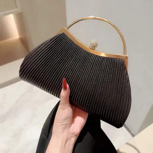 Svart plisserad clutch med guldhandtag och pärlformad knapp.