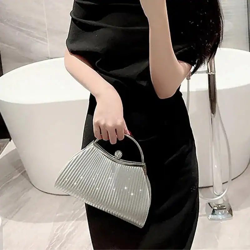 Beige plisserad clutch med silver glittr, perfekt för kvällsklänning och festlig tillfälle.