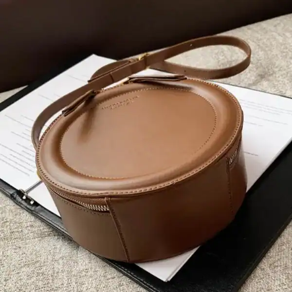Beige rund väska i läder med axelrem, elegant och trendig för vardag.