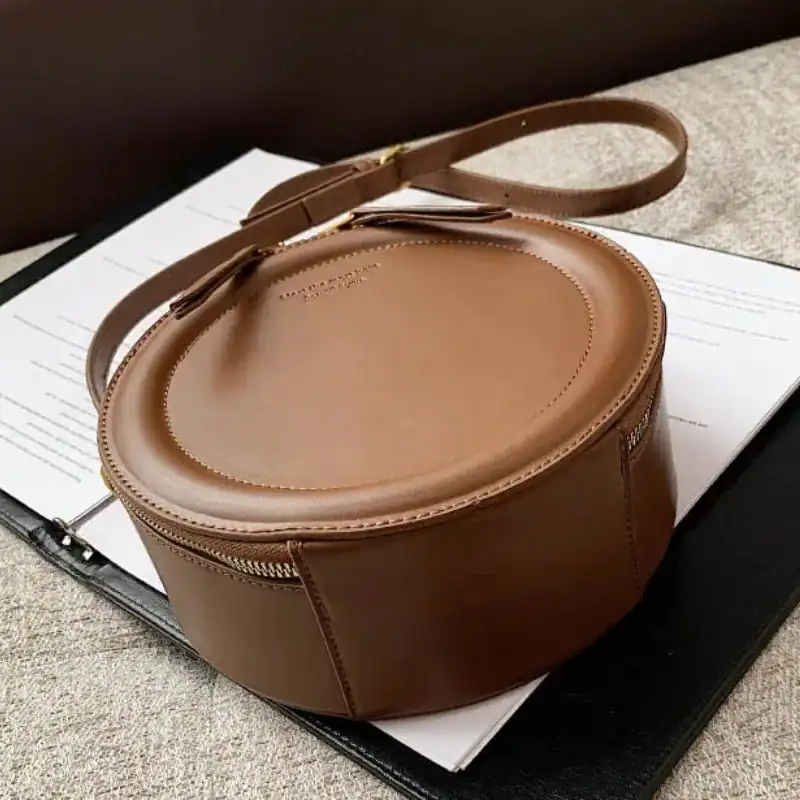 Beige rund väska i läder med axelrem, elegant och trendig för vardag.