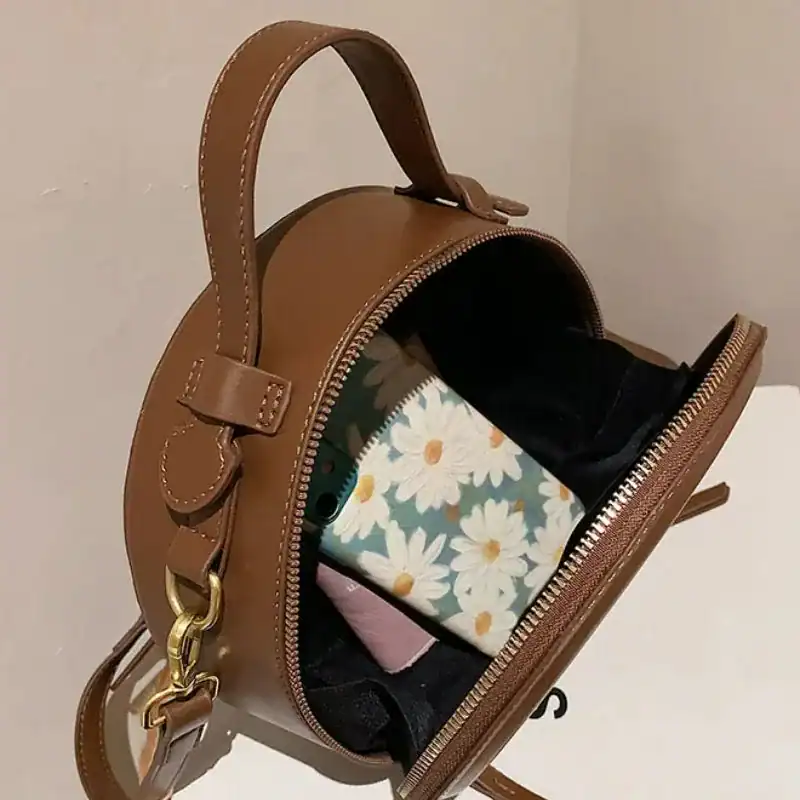 Beige rund väska med öppen ficka och blommig plånbok.