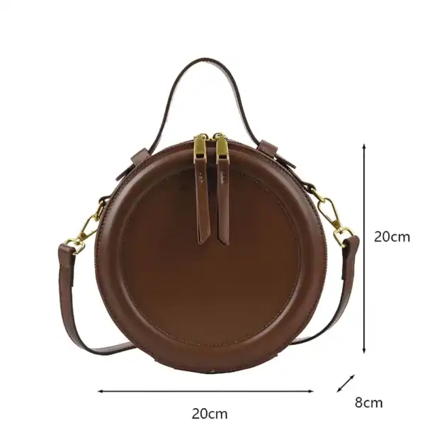 Brun rund axelväska med axelrem, 20 cm diameter, läderliknande material.