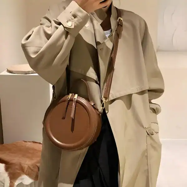 Beige rund väska med brun läderrem, modeaccessoarer för kvinnor.