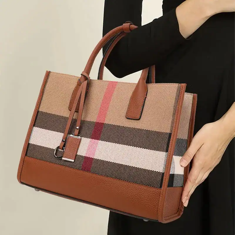 Beige rutig handväska med bruna handtag och textilplatta.